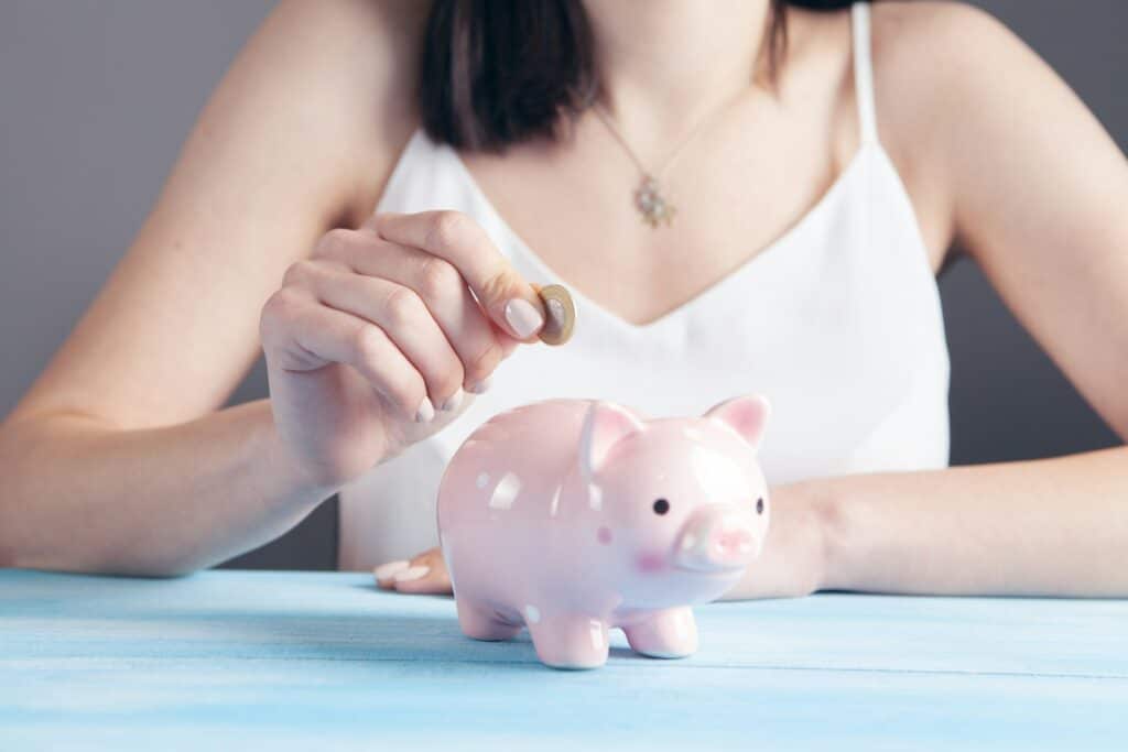 person putting a coin in a piggy bank to build an emergency fund