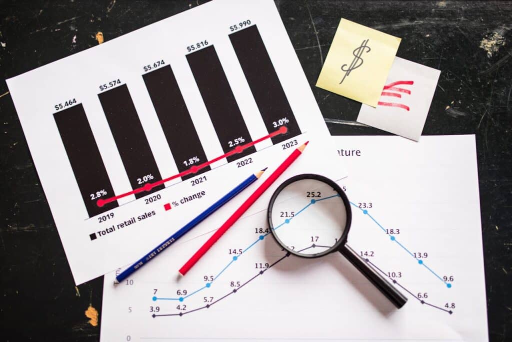 Magnifying glass on budget charts used to plan a weekly cash buffer.