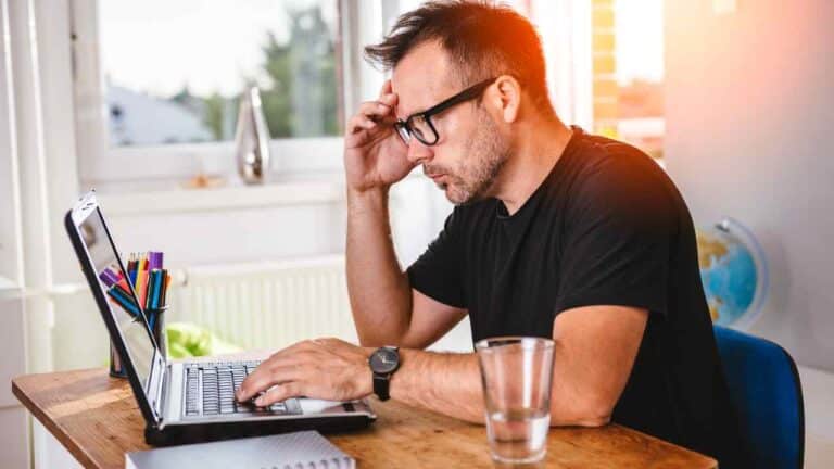 Person reviewing bills at home for “how much debt to file bankruptcy” article.