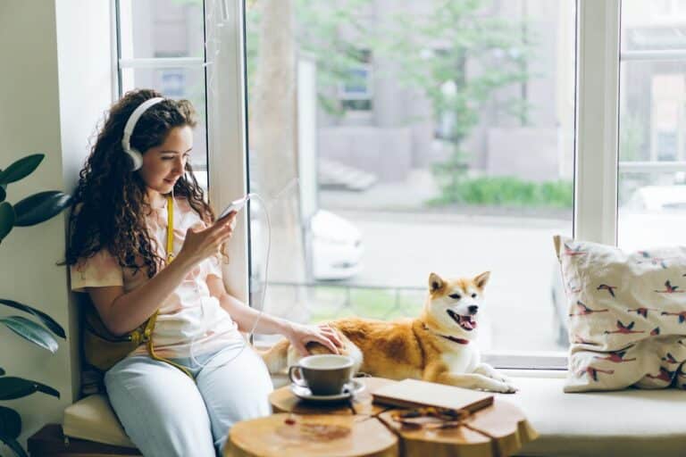 woman sitting next to dog with headphones